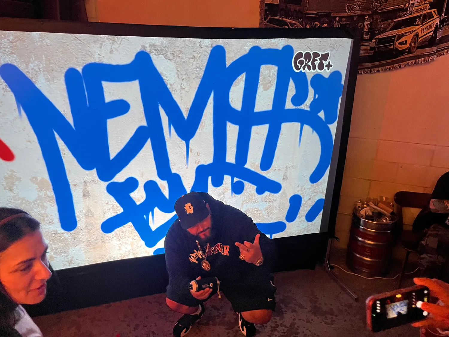Bold blue lettering painted live on the digital graffiti wall