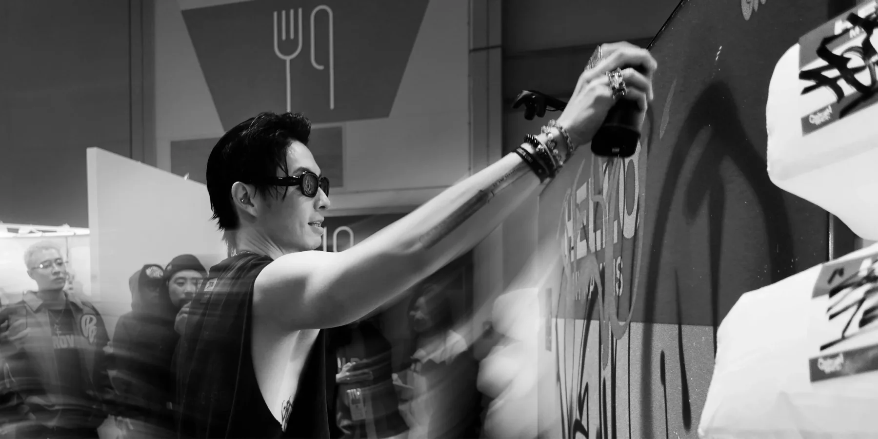 Carson Ting (Chairman Ting) painting live on the 100-inch 4K Graffiti+ canvas at ComplexCon Hong Kong 2025 — close-up in black-and-white with motion-blurred crowd