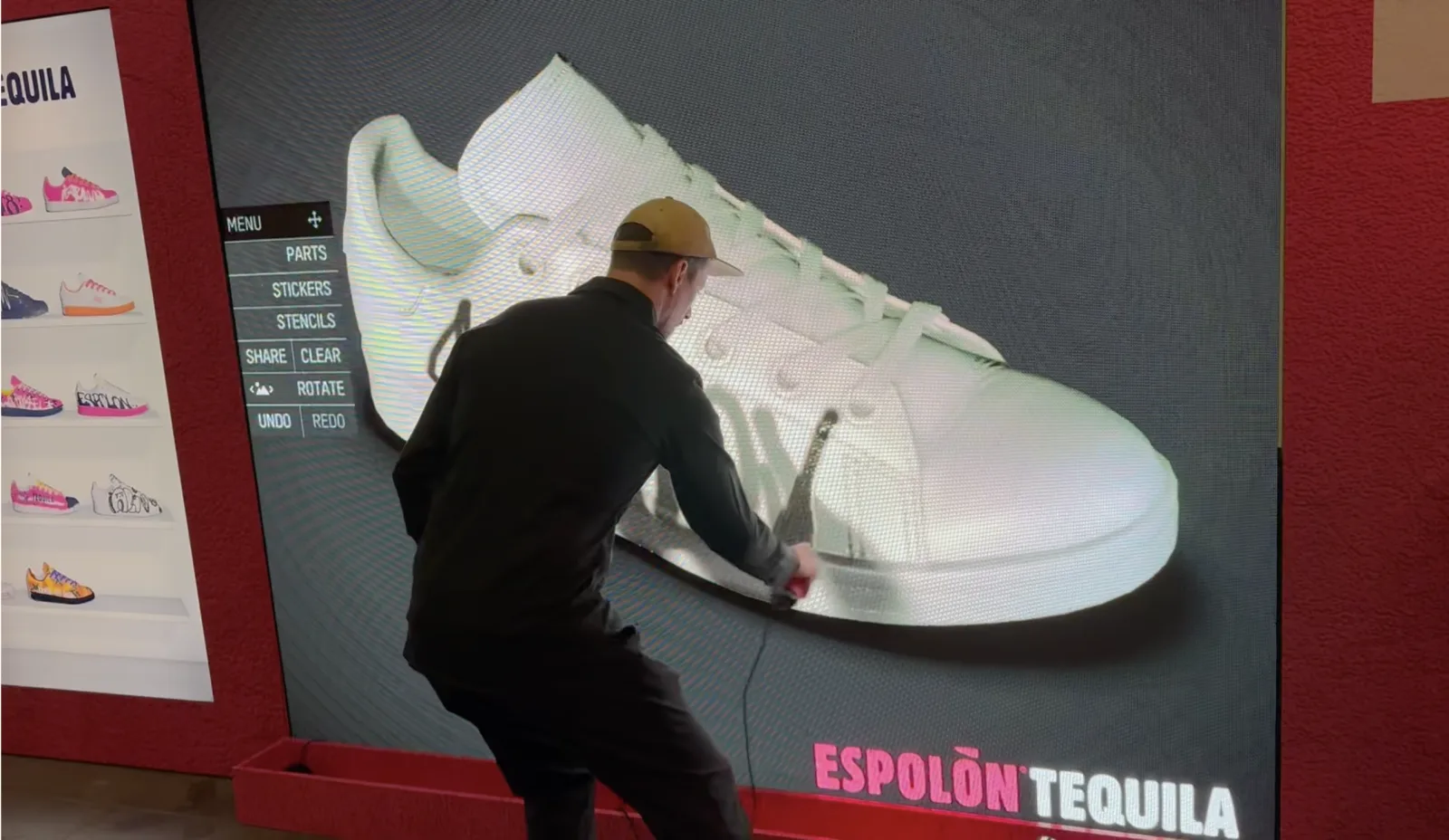 Guest live-spraying a giant 3D sneaker on the Graffiti+ wall at the Espolón Tequila booth, ComplexCon Las Vegas 2024 — UI menu (PARTS, STICKERS, STENCILS, SHARE, CLEAR, ROTATE, UNDO, REDO) visible on the left and a side rail of previously painted sneakers