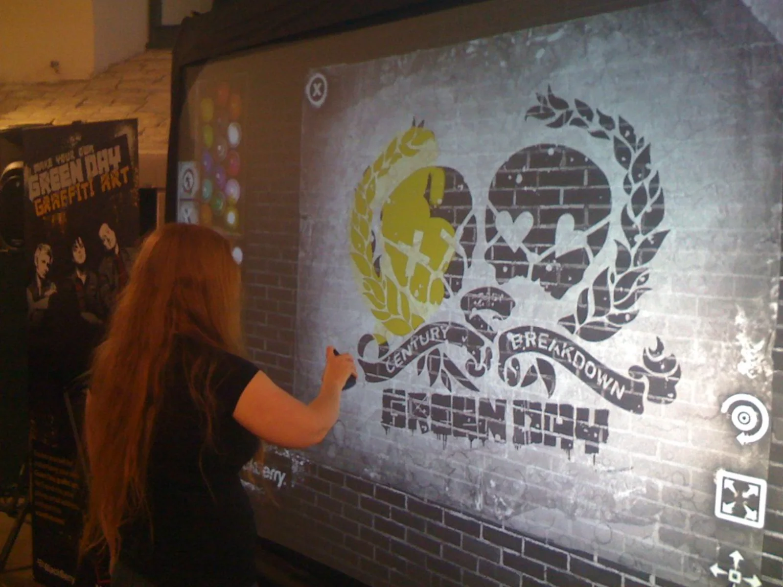 A fan spraying the 21st Century Breakdown heart-grenade emblem in yellow on the Graffiti+ digital wall, using the Green Day stencils and spray palette