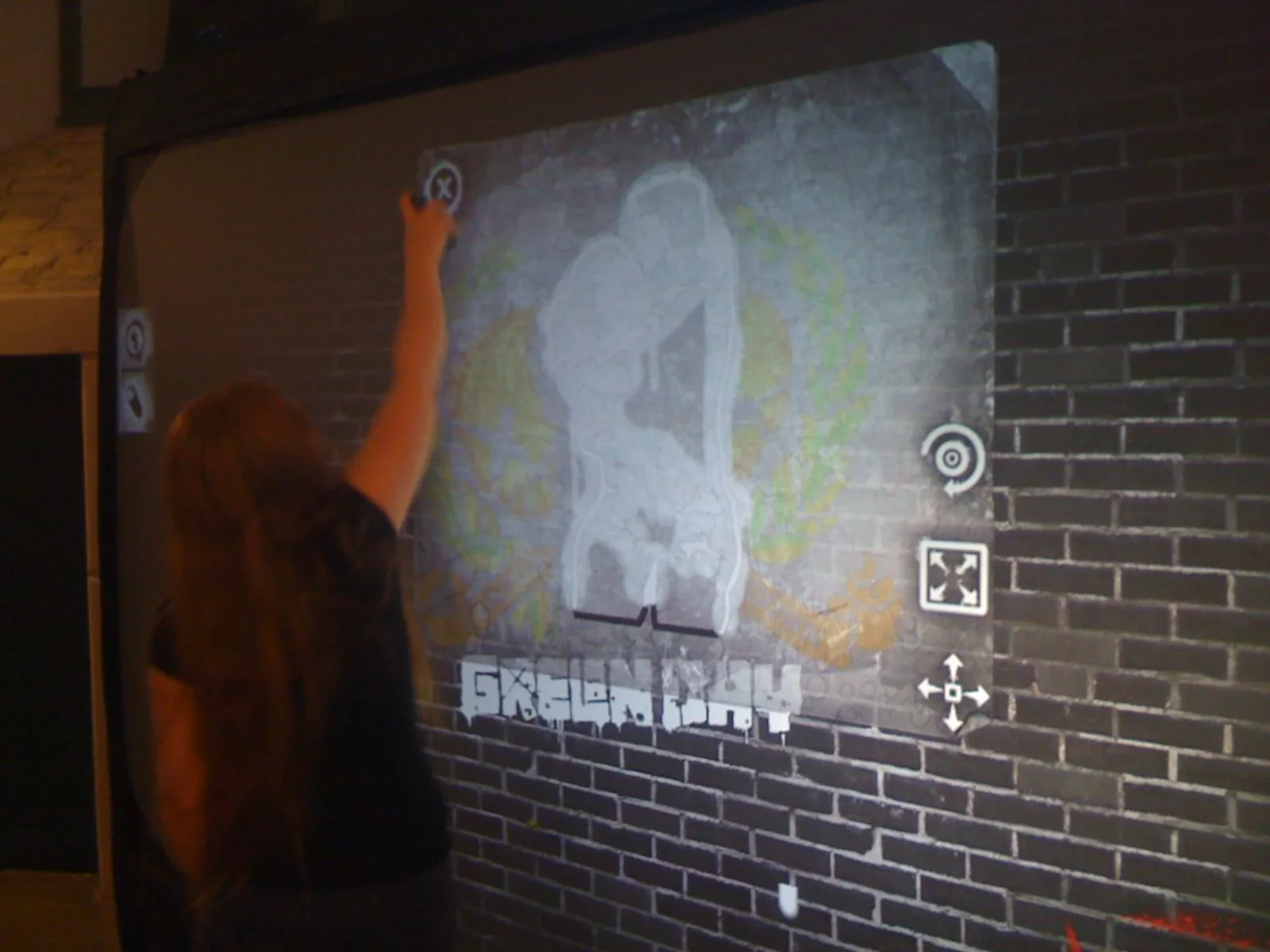 A fan spraying the couple-embracing album-cover stencil live on the Graffiti+ wall on the Green Day tour