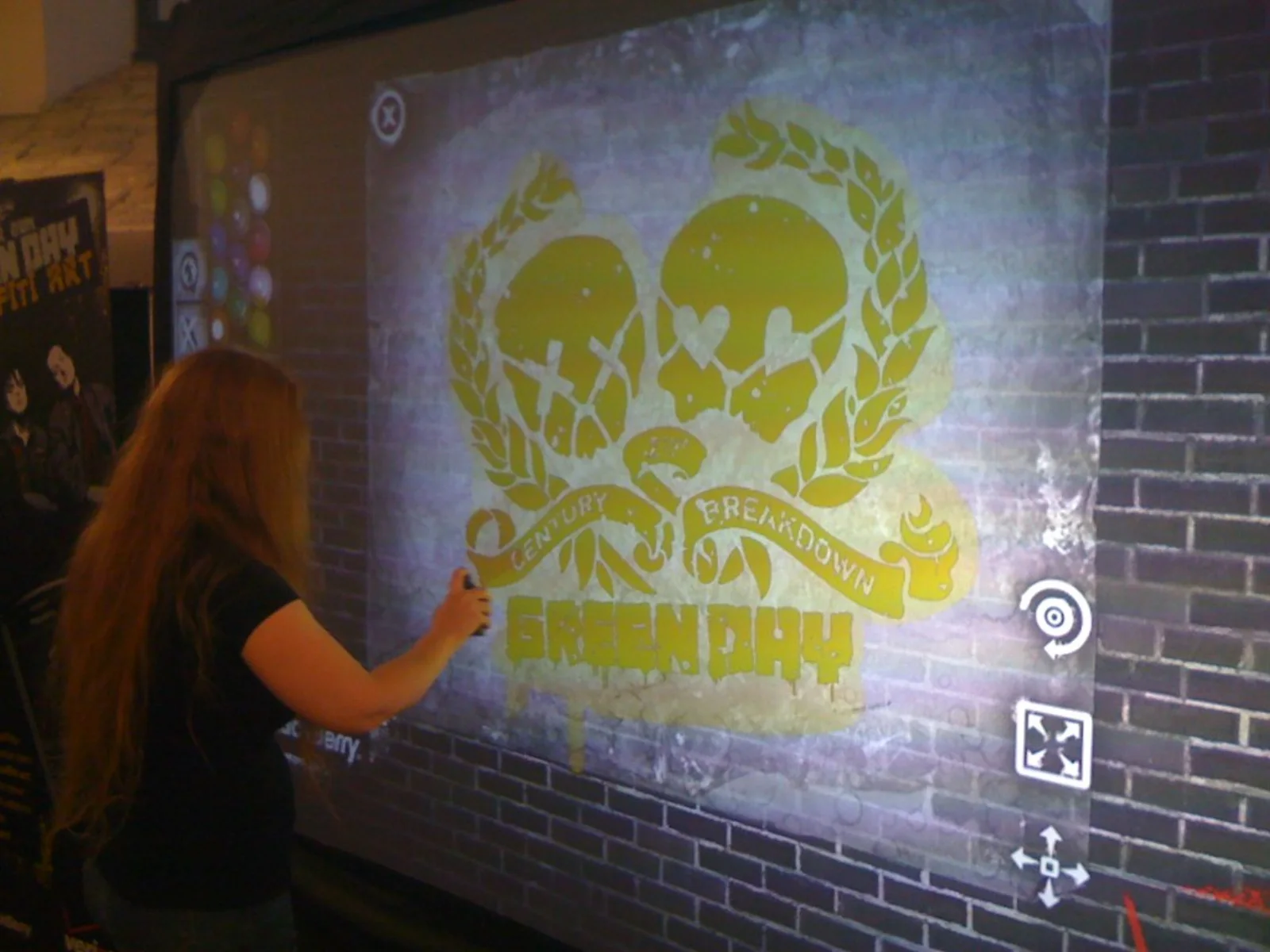 A fan painting the 21st Century Breakdown heart-grenade emblem in yellow using the Green Day stencils and spray palette on the digital wall