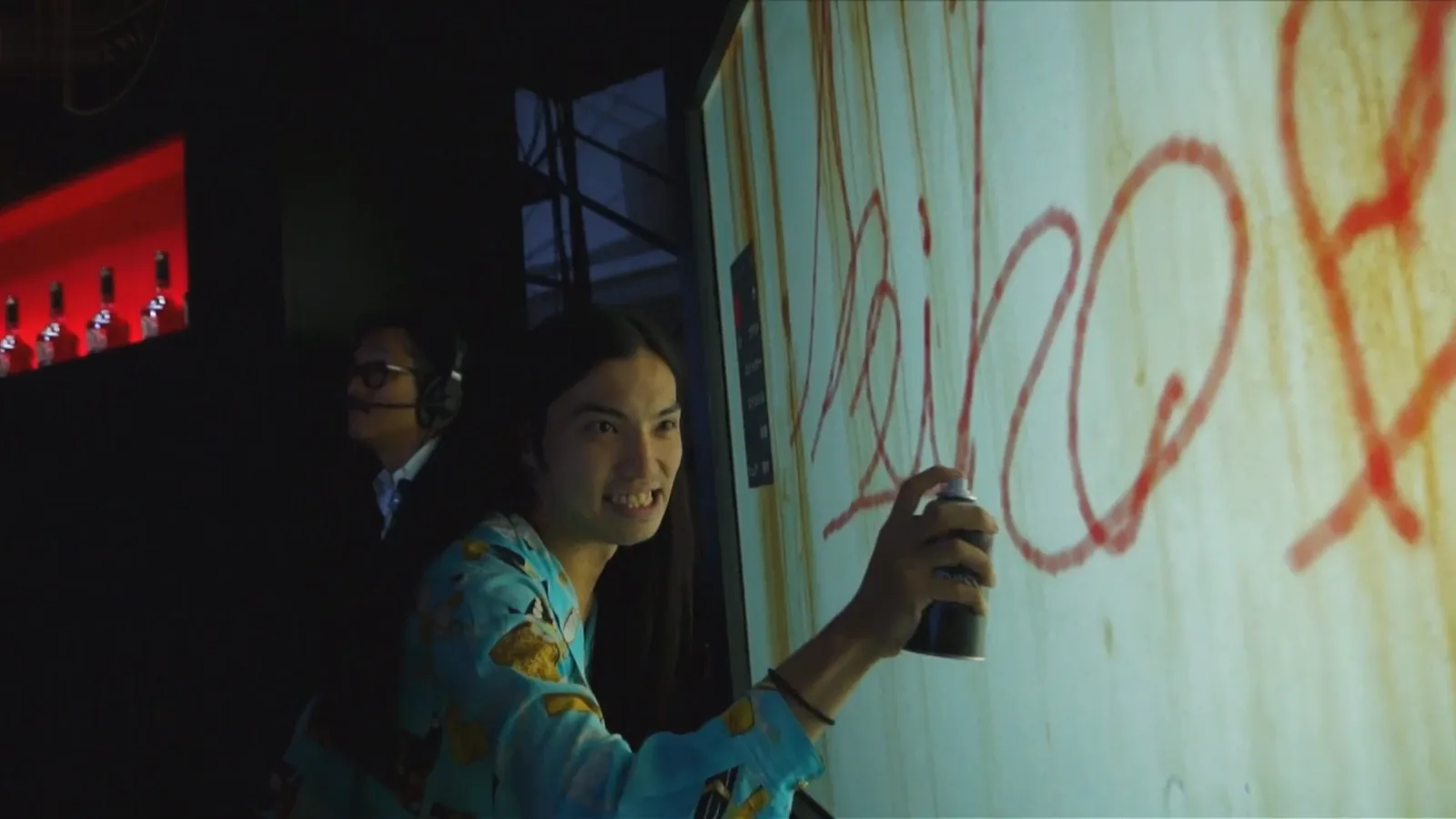 A guest in a kimono spray-painting live on the Graffiti+ digital wall, with a Hennessy bottle bar glowing behind, at the Hennessy x Shepard Fairey Tokyo launch, 2015