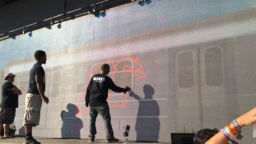 OG New York writer Meres One painting a piece on a full-size subway car projected across the 150-foot Graffiti+ LED wall at Panorama Festival, Randall's Island, 2016