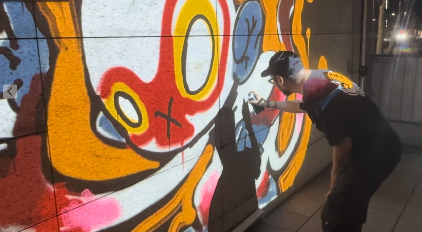 A visitor sprays a detailed character on the Infinite Graffiti wall