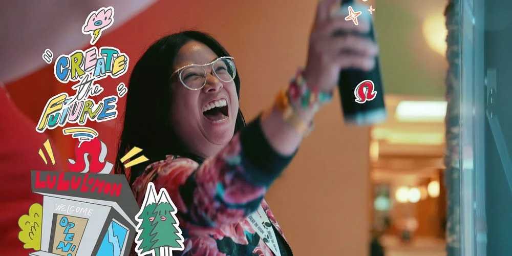 A Lululemon staff attendee laughing at the RMI Gathering 2023 — the Chairman Ting illustration set framing the moment